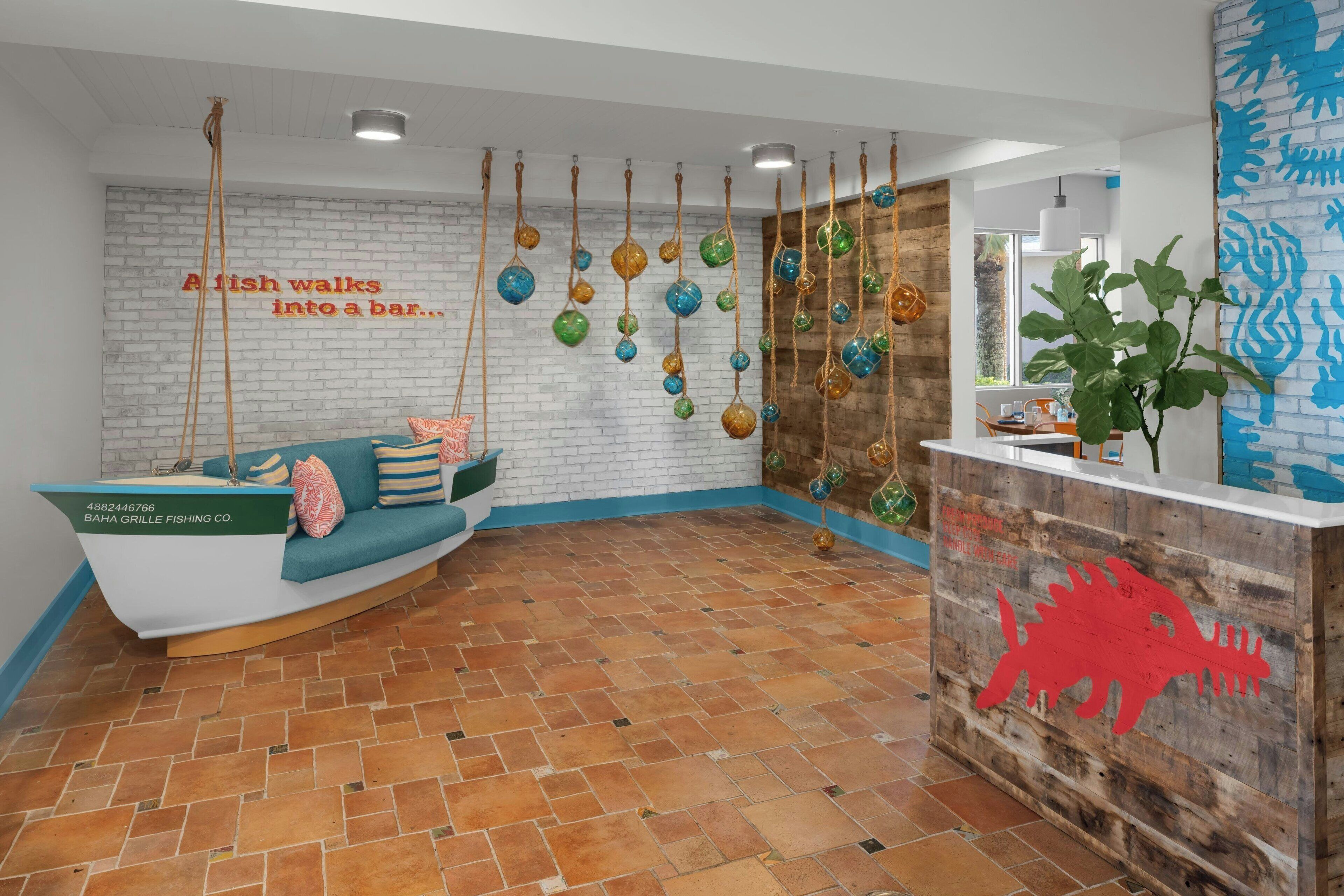 A reception area with a white brick wall, a wooden reception desk with a red fish decal, and hanging decorative fish.