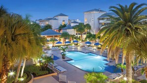 Un resort con piscina, sillones de descanso y palmeras.