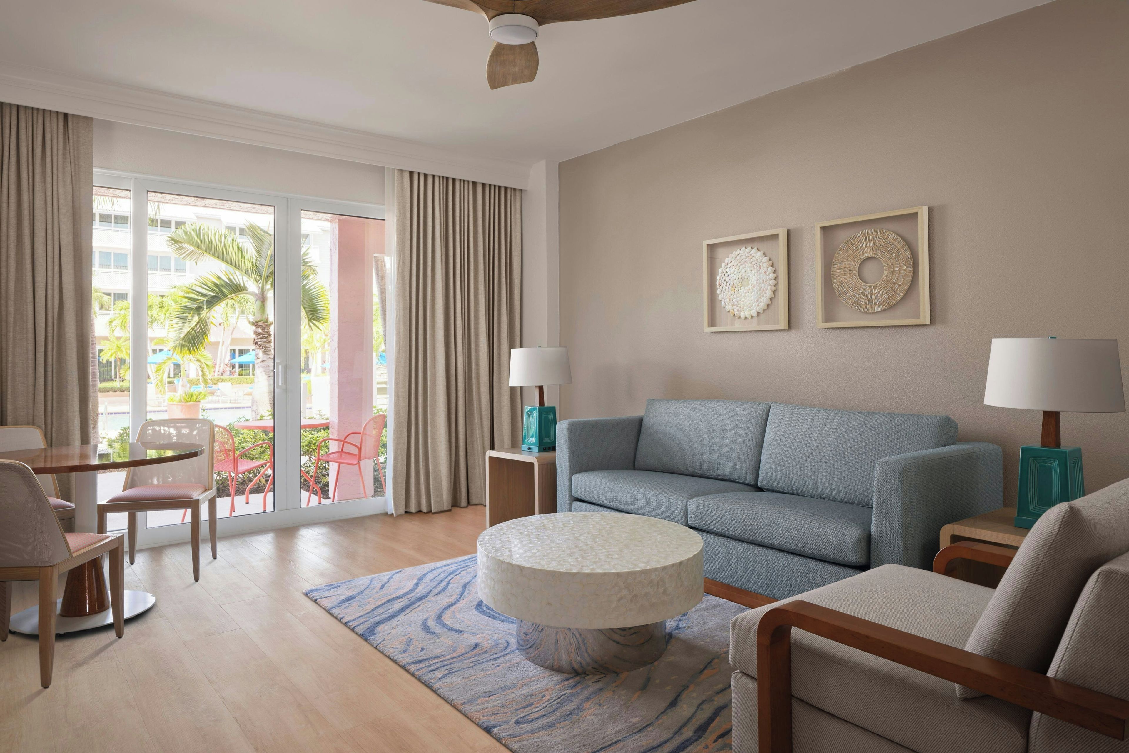 A modern living room with a grey sofa, a round coffee table, and a dining area with chairs and a table.