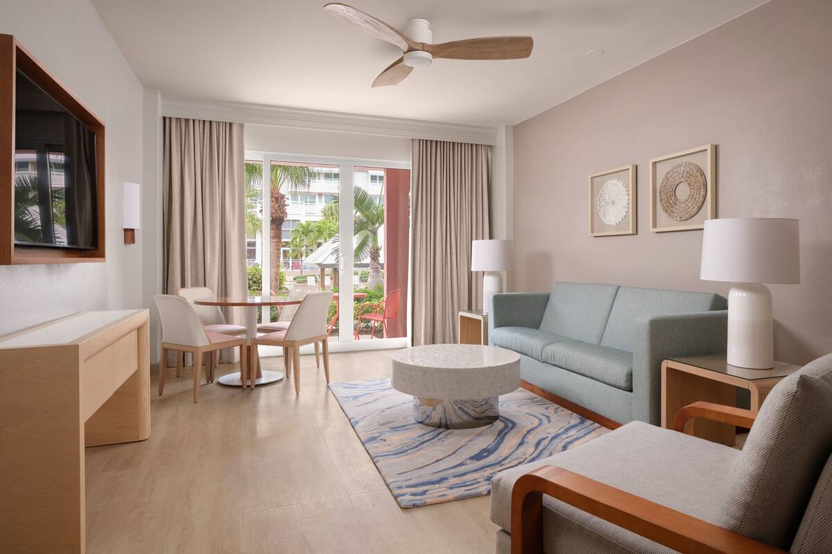 Habitación de hotel con comedor, sofá, una mesa redonda de centro y ventilador de techo.