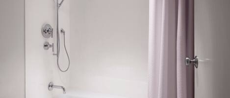 A modern bathroom with a white bathtub, a showerhead, and a handheld shower attachment.