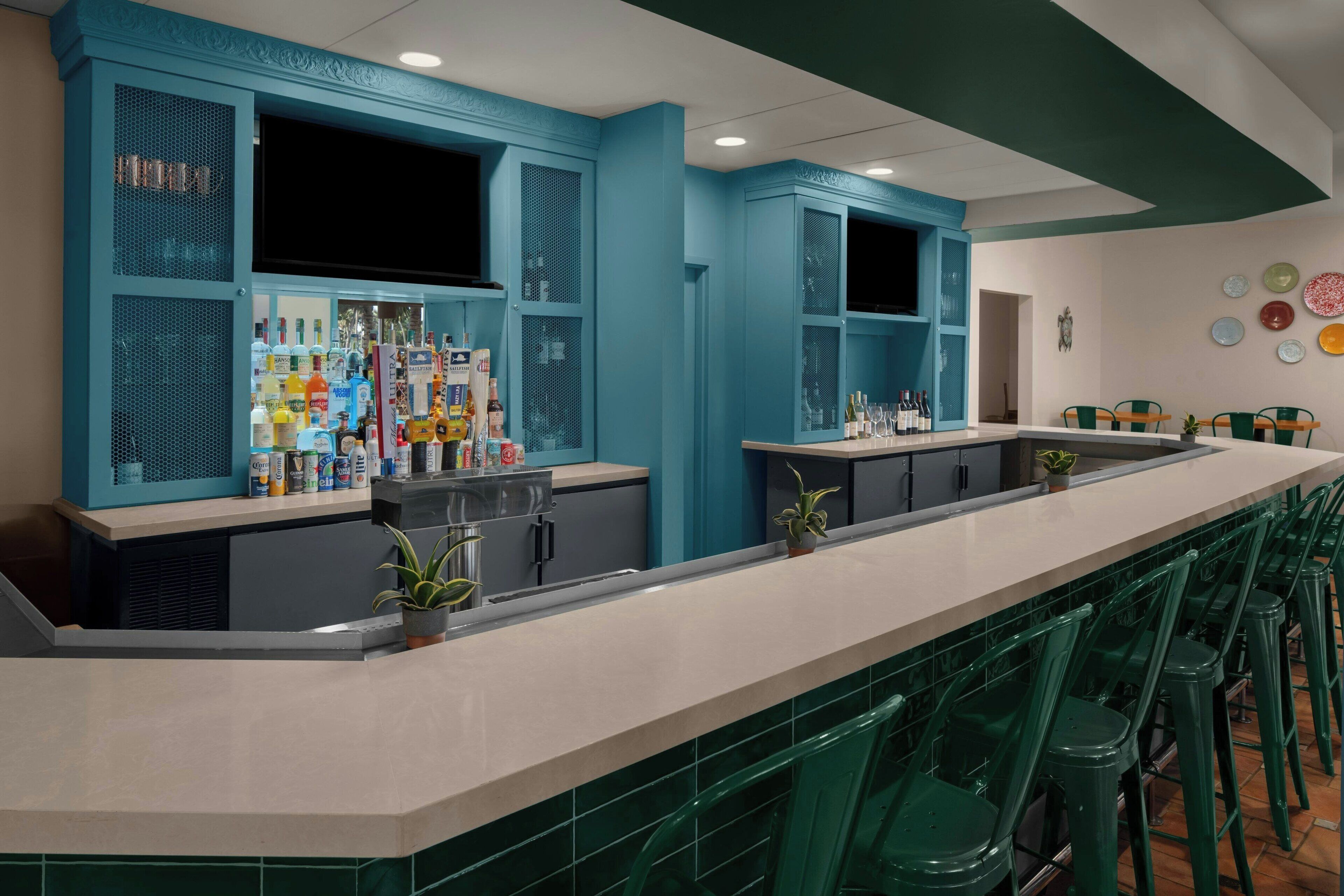 A bar area with a counter, stools, and shelves stocked with bottles.
