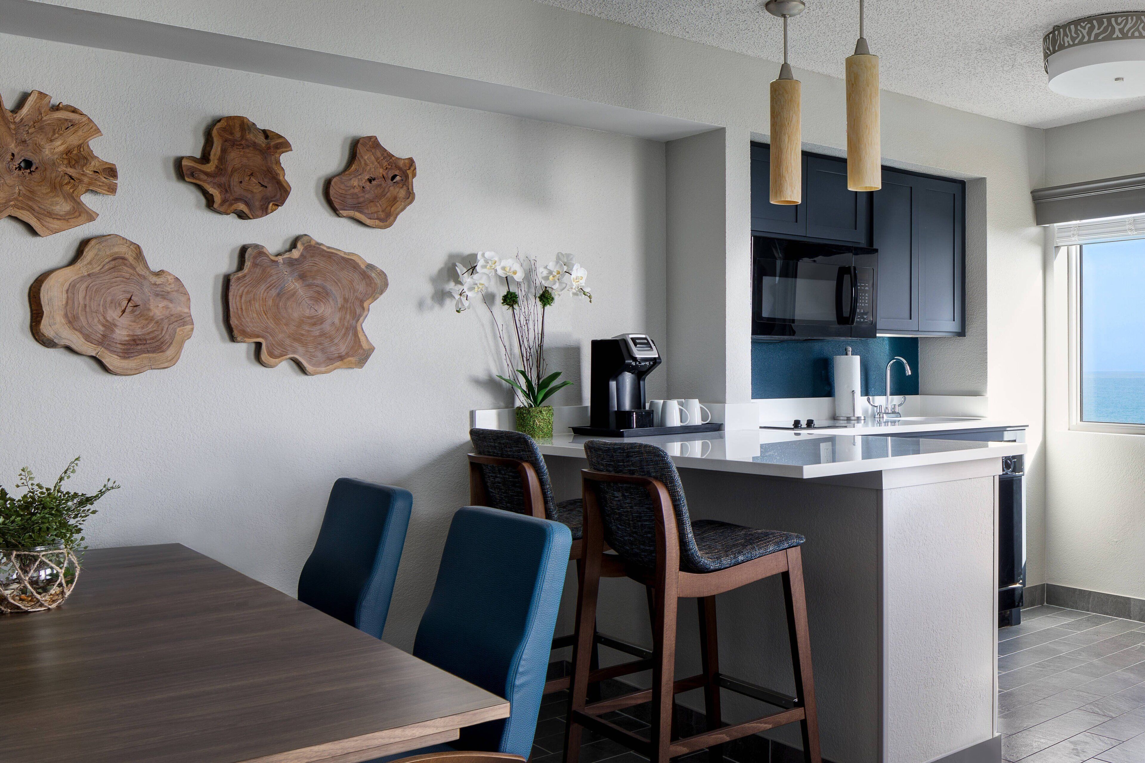 A modern kitchen with a central island, dark cabinetry, and pendant lighting.