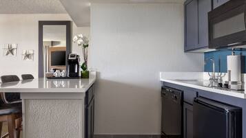 A modern kitchen with a white countertop, dark cabinets, and a built-in dishwasher.
