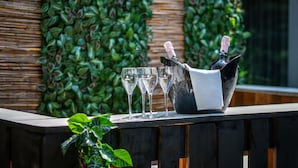 Una zona de bar con mostrador de madera, un cubo negro con dos botellas de champán y tres copas vacías.