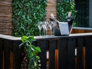 A bar area with a wooden counter, a black bucket holding two bottles of champagne, and three empty glasses. - ibis Styles Linz (Linz)