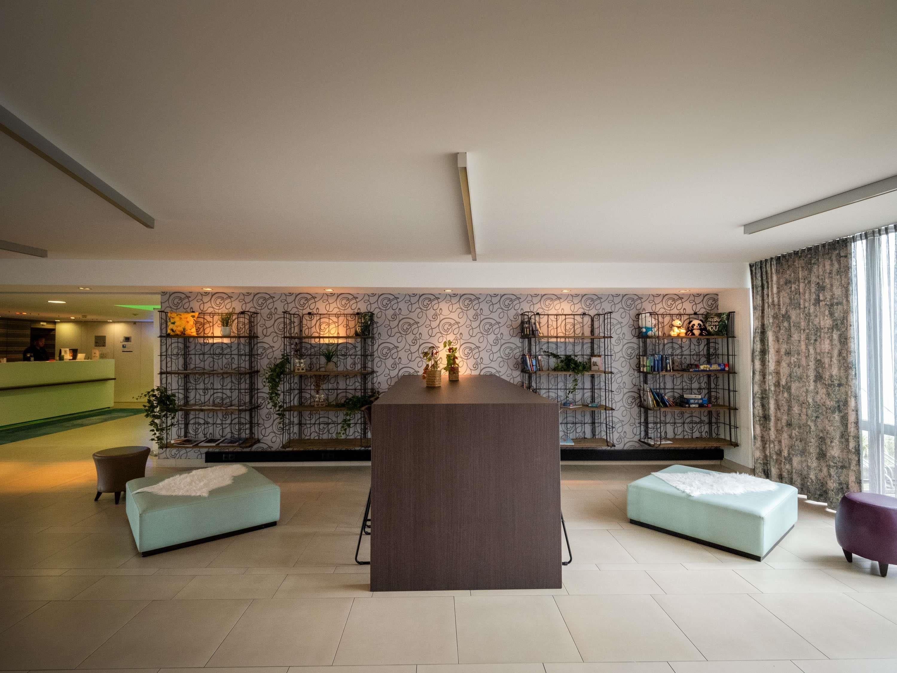 A modern lobby with a reception desk, seating areas, and decorative shelves.