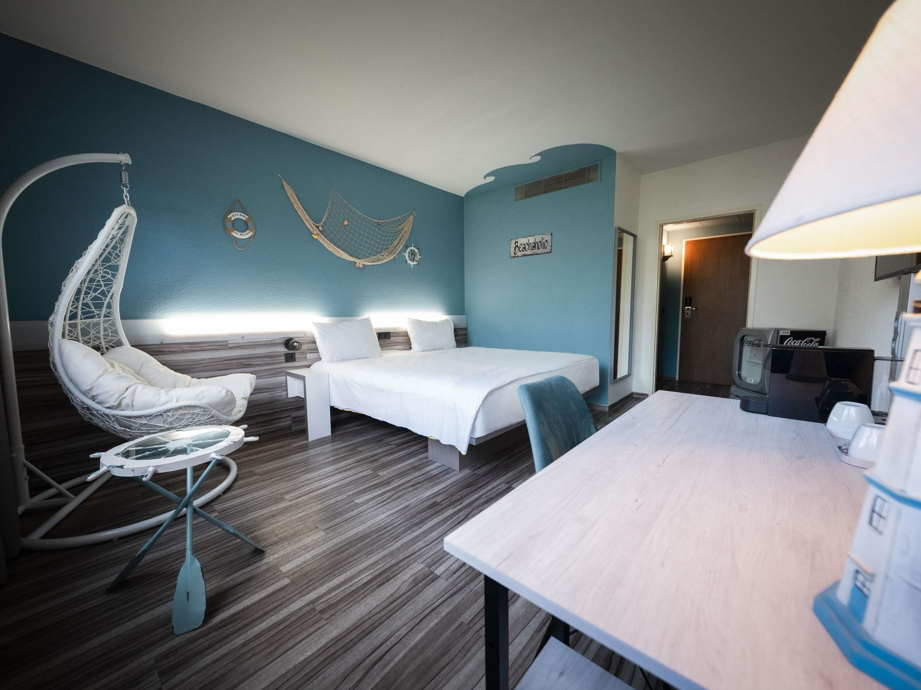 Ein Zimmer mit einem Bett, einem Hängesessel, einem kleinen Tisch und einem Fernseher.