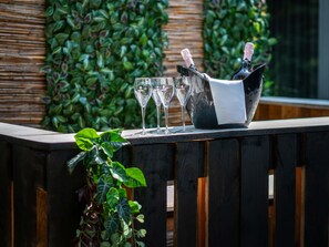 Una zona de bar con mostrador de madera, un cubo negro con dos botellas de champán y tres copas vacías.