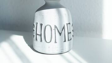 Una lámpara blanca con pantalla cilíndrica y una base con la palabra 'HOME' escrita.
