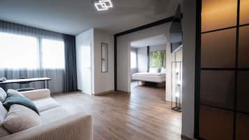 Una habitación de hotel moderna con sofá, una mesa de comedor y un ventanal grande.