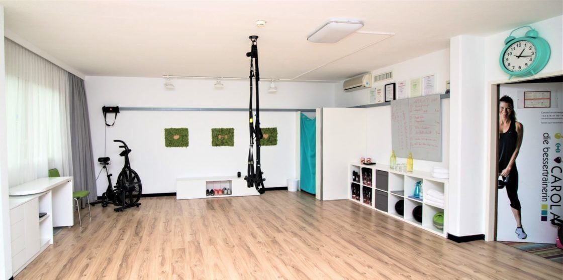 Ein geräumiges Zimmer mit Holzboden, Trainingsgeräten, einer Wandtafel und einer Uhr an der Wand.