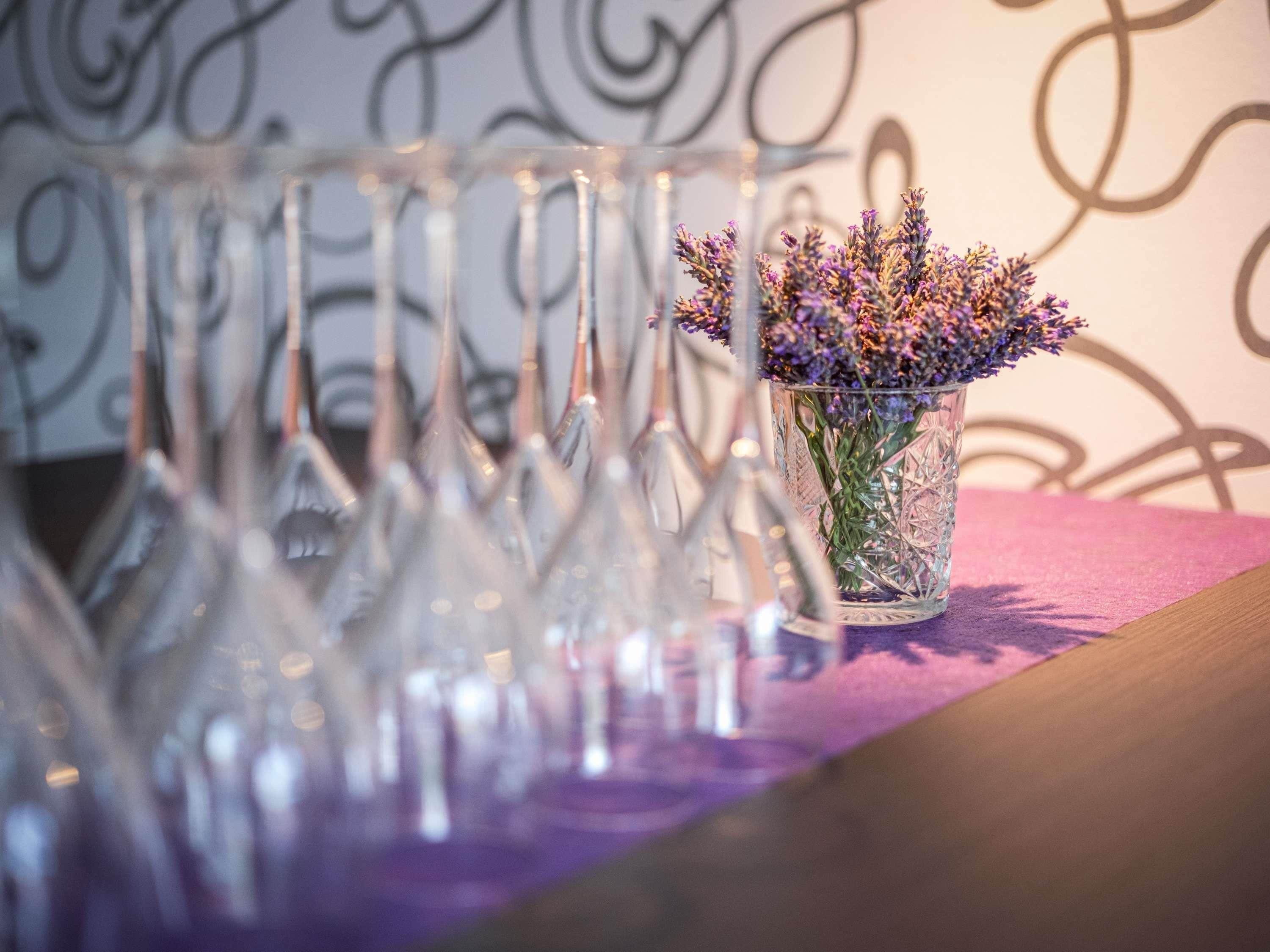 A clear glass vase with lavender flowers on a table.