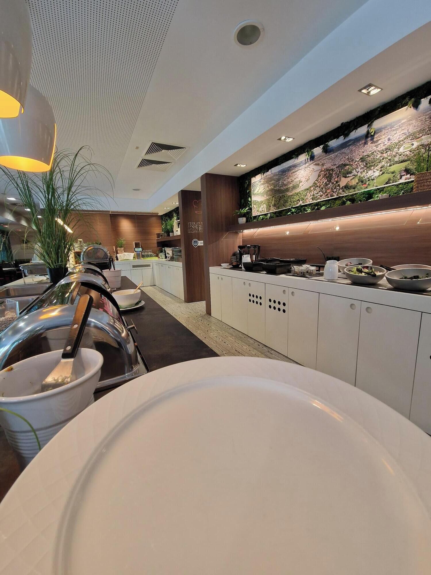 A modern restaurant with a view of a cityscape, white cabinets, and a large aquarium.
