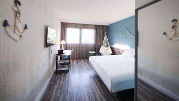 Habitación de hotel con cama, escritorio, silla, sillón colgante y decoración náutica.