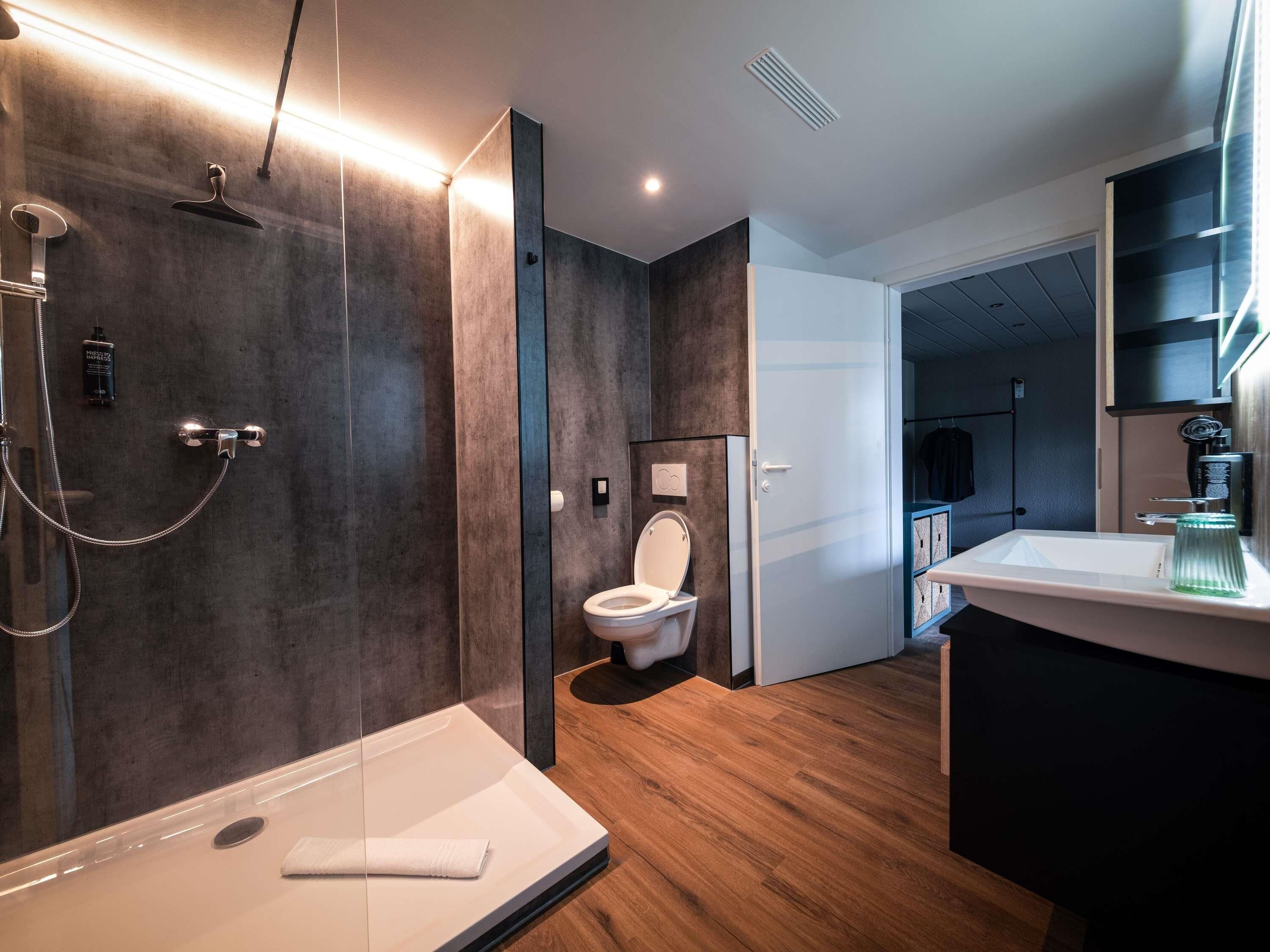 Une salle de bain moderne avec une douche à l’italienne, des toilettes et un lavabo.