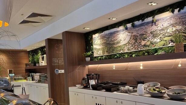 A modern buffet setup with a variety of food items, a large wall-mounted map, and a wooden accent wall. - ibis Styles Linz (Linz)