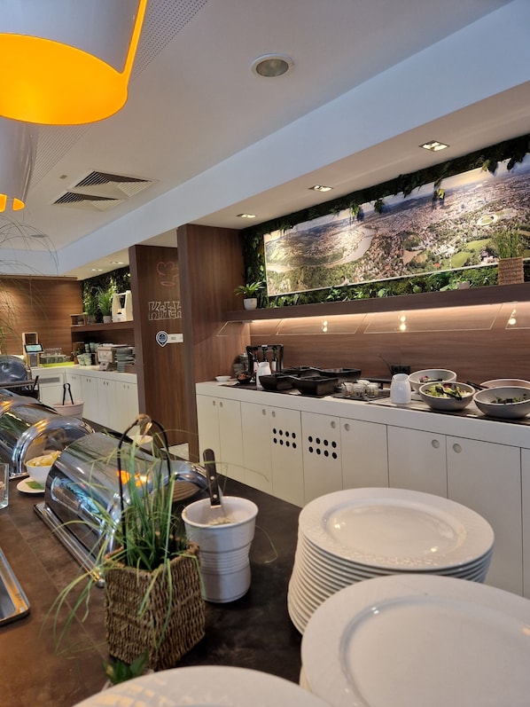 A modern buffet setup with a variety of food items, a large wall-mounted map, and a wooden accent wall. - ibis Styles Linz (Linz)