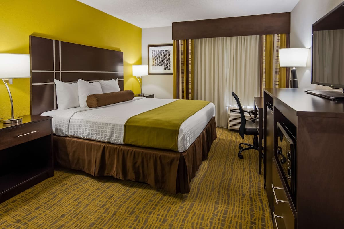 Een hotelkamer met een bed, nachtlampjes, een bureau met een computer en een televisie.