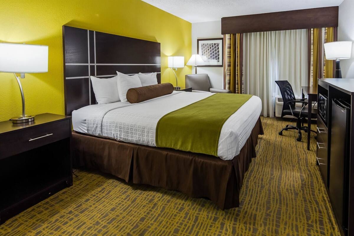 Een hotelkamer met een bed, bureau, stoel en televisie.