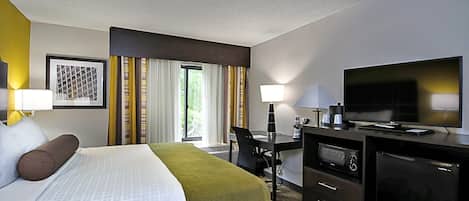 Ein Hotelzimmer mit Bett, Schreibtisch, Fernseher und kleinem Kühlschrank.
