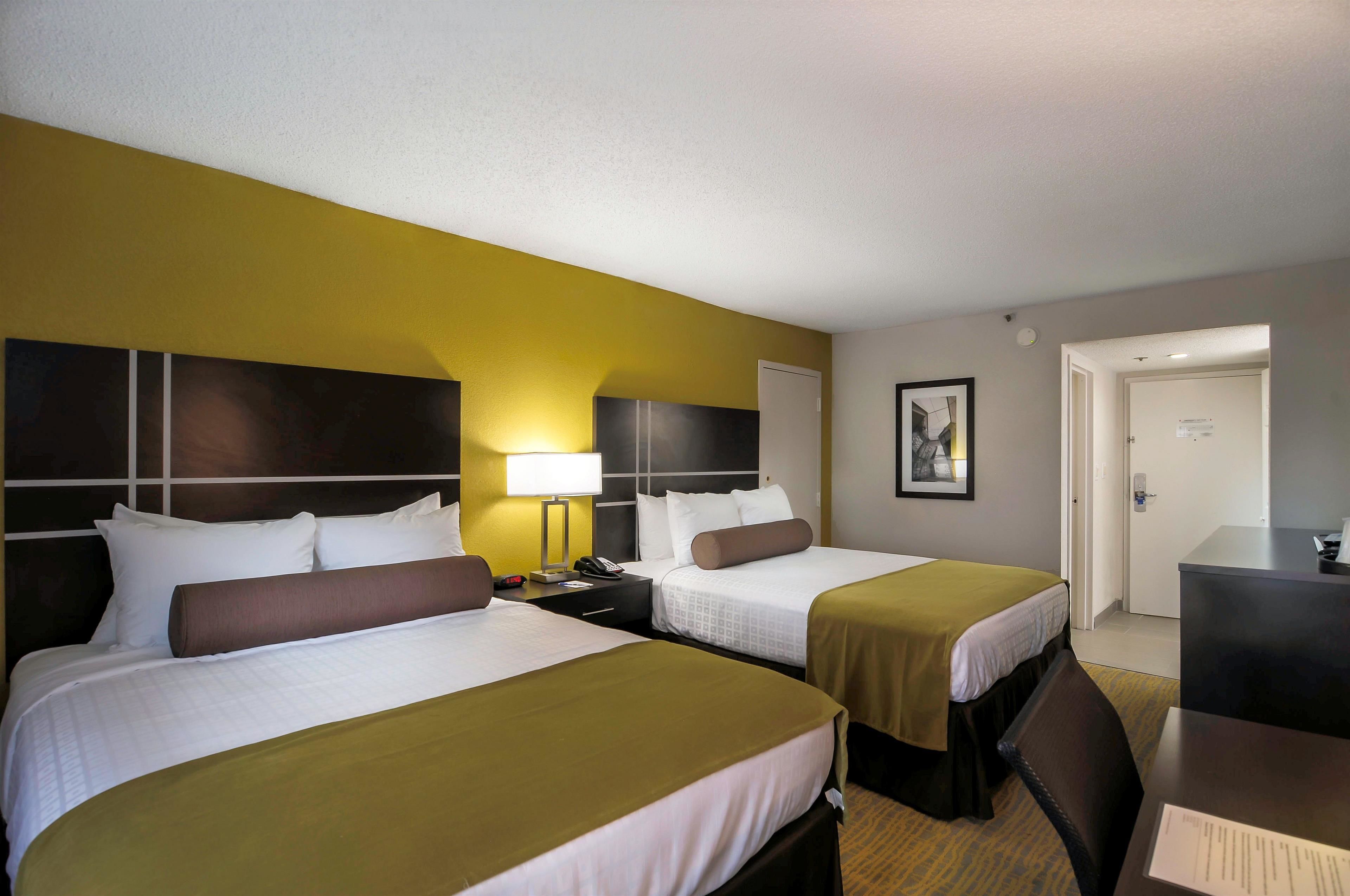 A hotel room with two beds, a desk, and a chair.