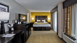 A hotel room with a bed, bedside tables, a desk with a coffee maker, a TV, and a window with curtains. - Best Western Plus Hanes Mall Hotel (Winston-Salem)