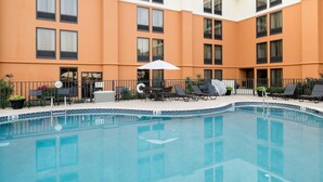 A hotel pool area with a clear blue pool, lounge chairs, and umbrellas. - Comfort Inn & Suites Newark - Wilmington (Newark)