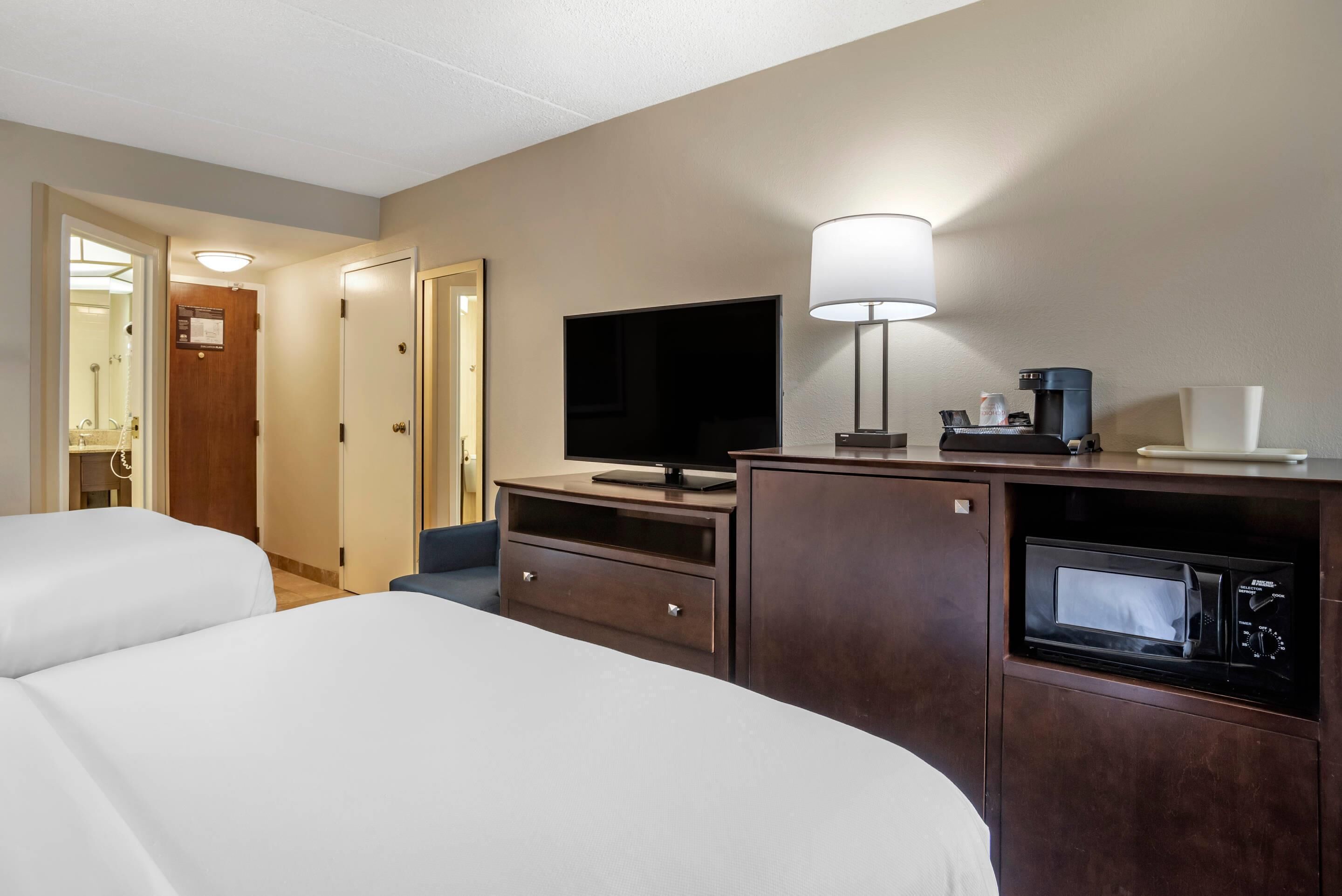 Een hotelkamer met twee bedden, een televisie, een koffiezetapparaat en een magnetron.