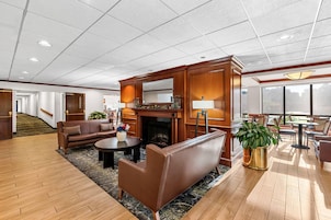 A spacious lobby with a fireplace, leather sofas, a coffee table, and a large window providing a view.
