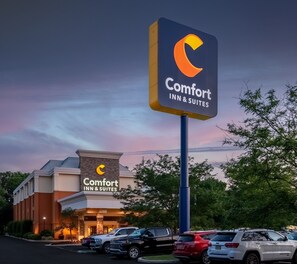 Ein Comfort Inn & Suites Hotel mit auffälligem Schild, Parkplatz und umliegenden Bäumen.
