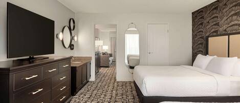 A hotel room with a large bed, a dresser, a flat-screen TV, and a patterned carpet.