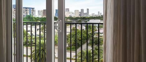 Un balcón con vistas a un horizonte urbano, palmeras y una calle.