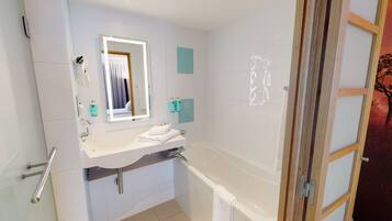 Een moderne badkamer met een wit wastafel, spiegel en bad. Op het aanrecht staan twee flessen shampoo en een handdoek.