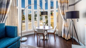 A modern room with a round table, four chairs, a blue sofa, and a floor lamp. - Century Park Hotel (Los Angeles)