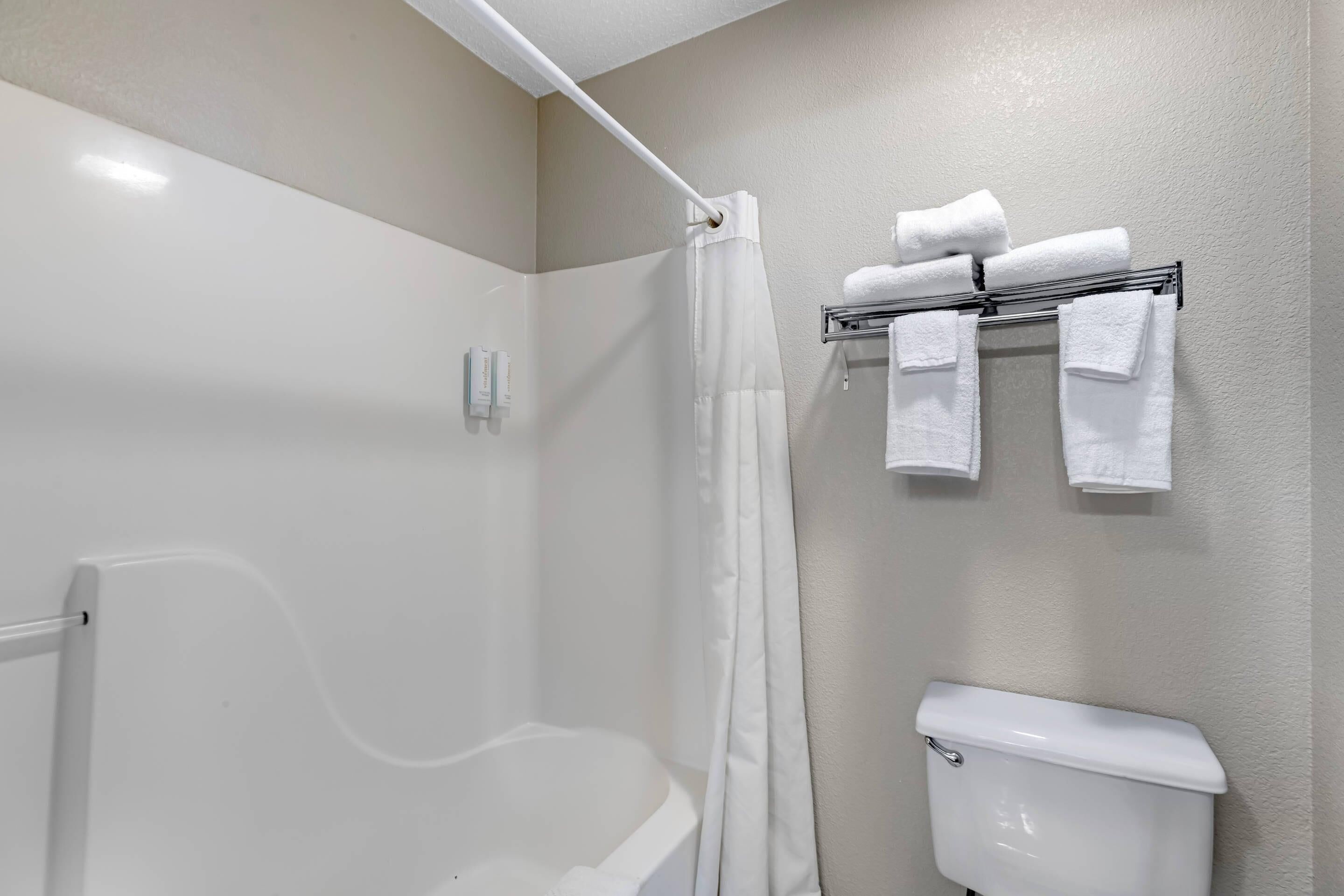 Un baño con ducha, inodoro y toallero con toallas.