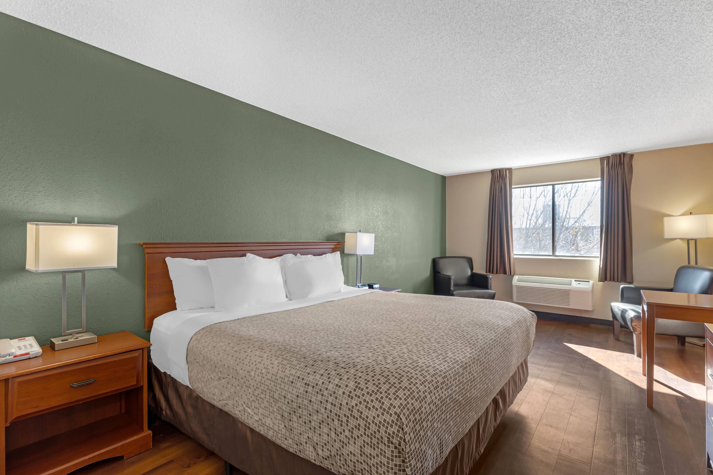 A hotel room with a large bed, bedside tables, a desk, and a chair.