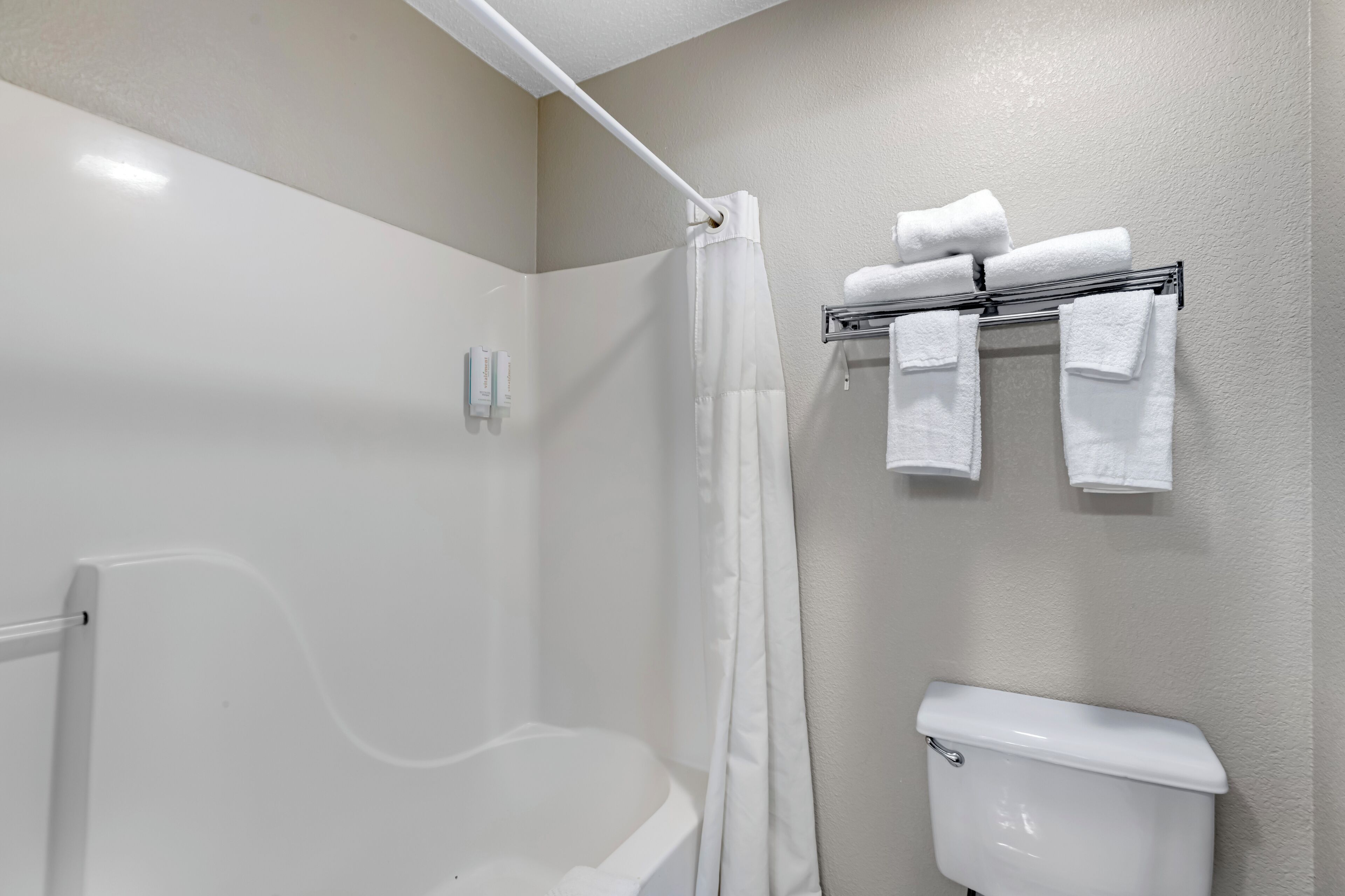 A bathroom with a shower, a toilet, and a towel rack with towels.