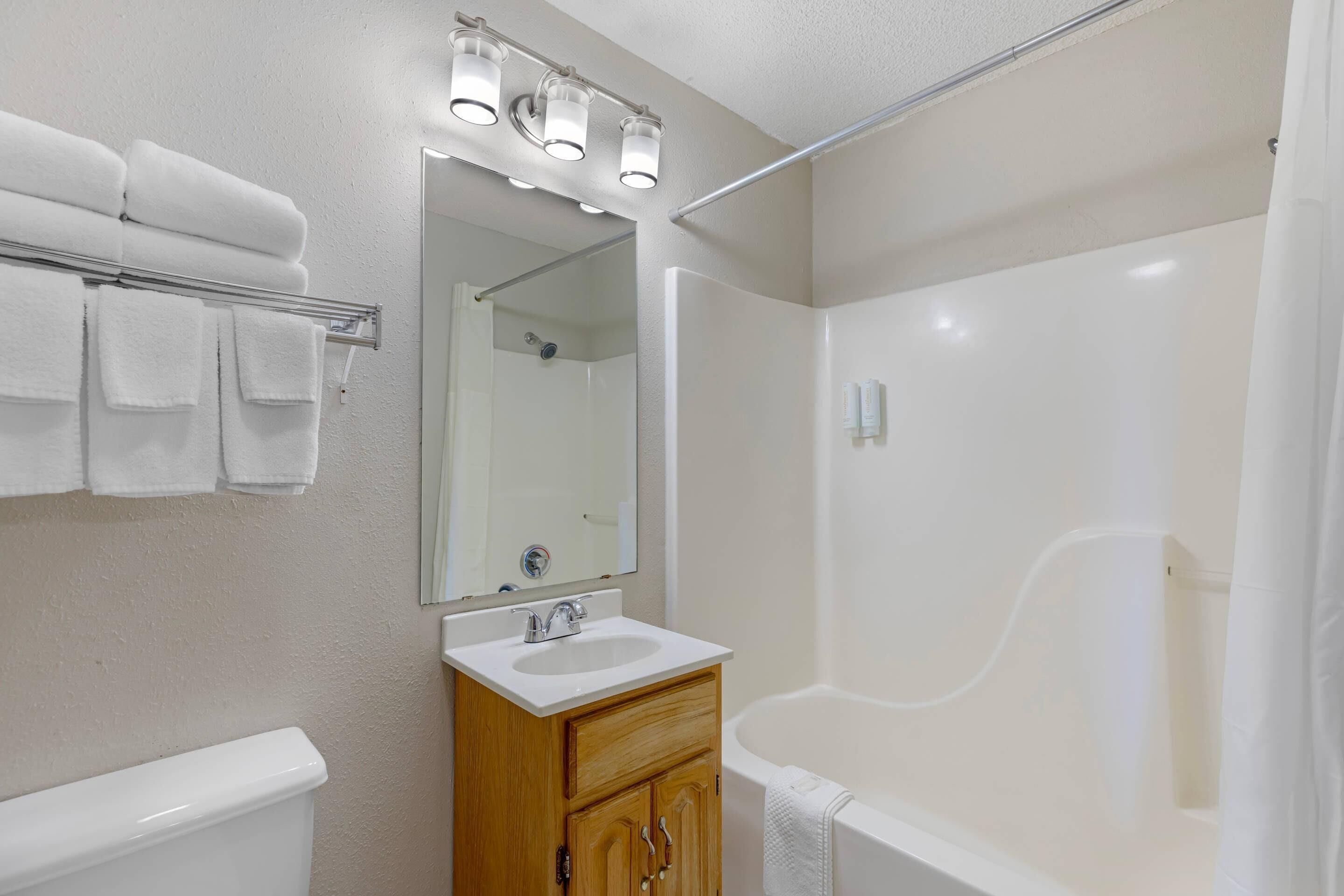 Un baño con lavamanos, espejo, toallero y bañera.