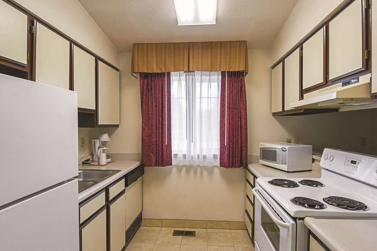 A compact kitchen with a refrigerator, microwave, stove, and sink.