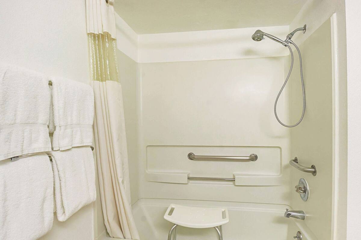 A bathroom with a bathtub, a shower, and a small stool.