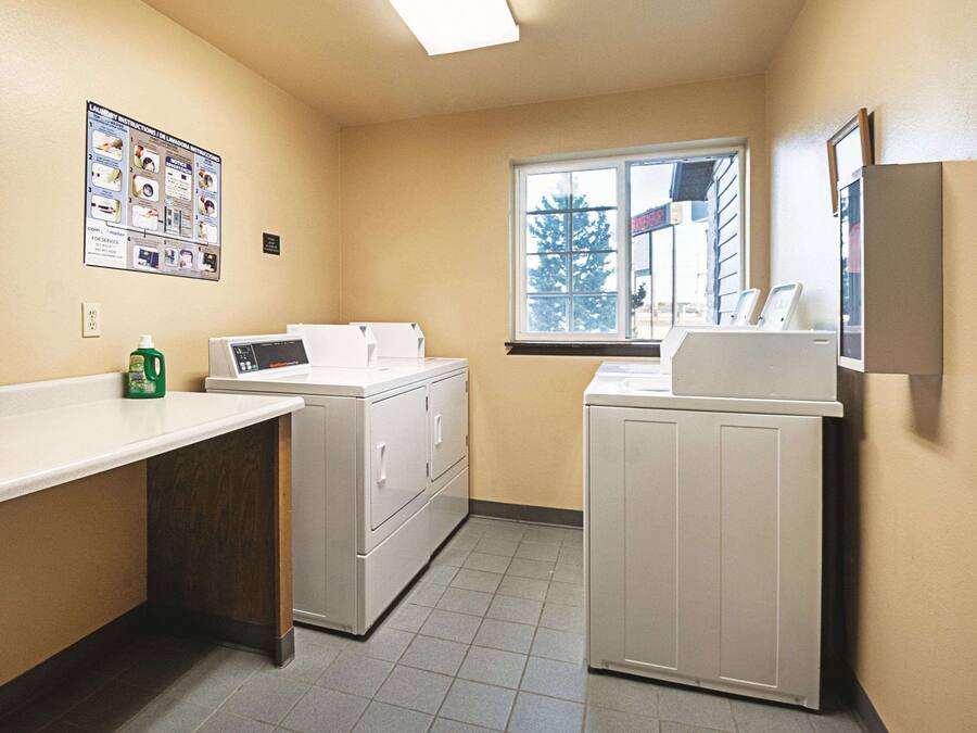 A laundry room with a washing machine, dryer, and a window with a view of a building outside.