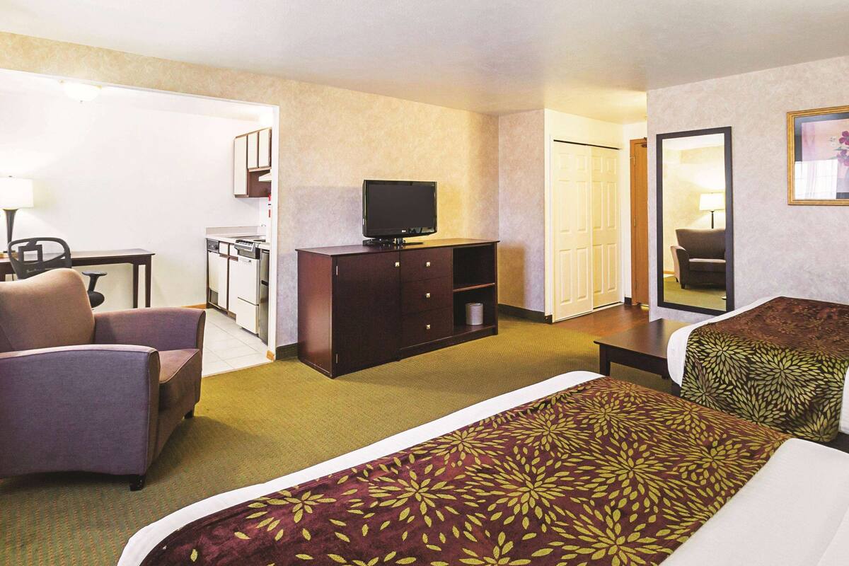 A hotel room with a bed, a chair, a desk with a television, and a wardrobe.
