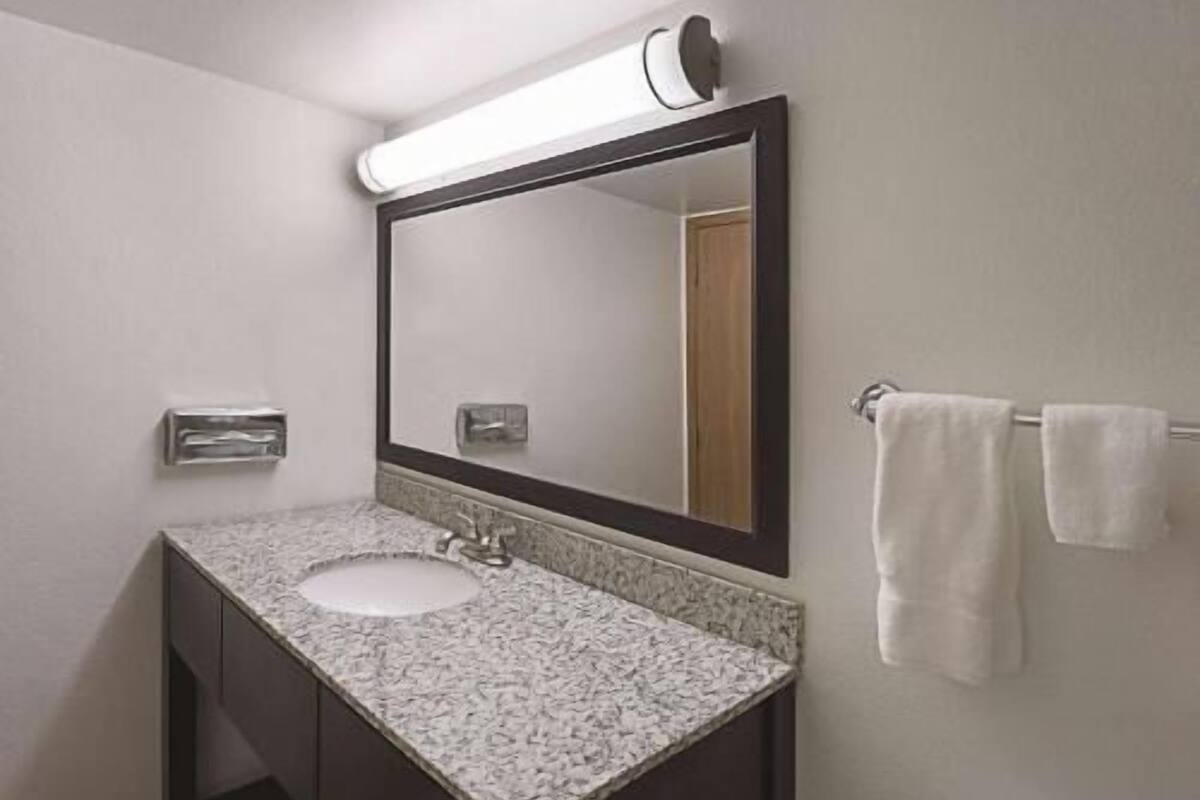 A bathroom with a sink, mirror, towel rack, and a light fixture.