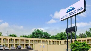 Een motel met een bord waarop 'WHITE ROCK INN' staat en een rij gelijkvloerse gebouwen met balkons.