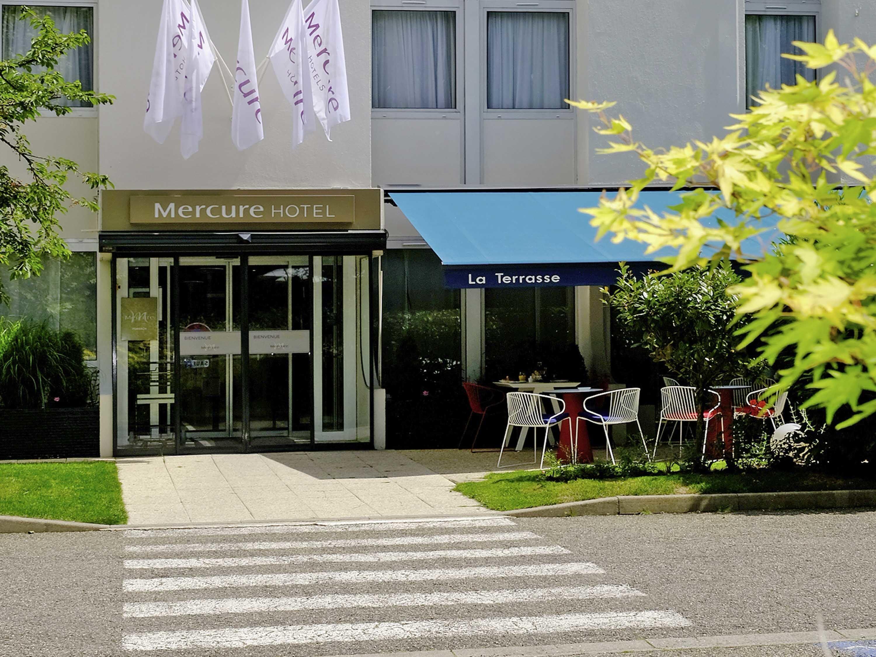 The exterior of Mercure Hotel with a clear entrance, a terrace area with outdoor seating, and a sign indicating the hotel's name.