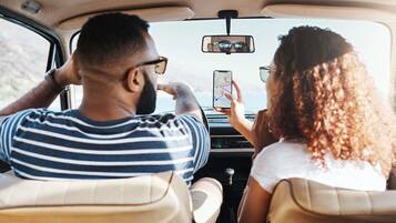 A car interior with two passengers, one holding a smartphone.
