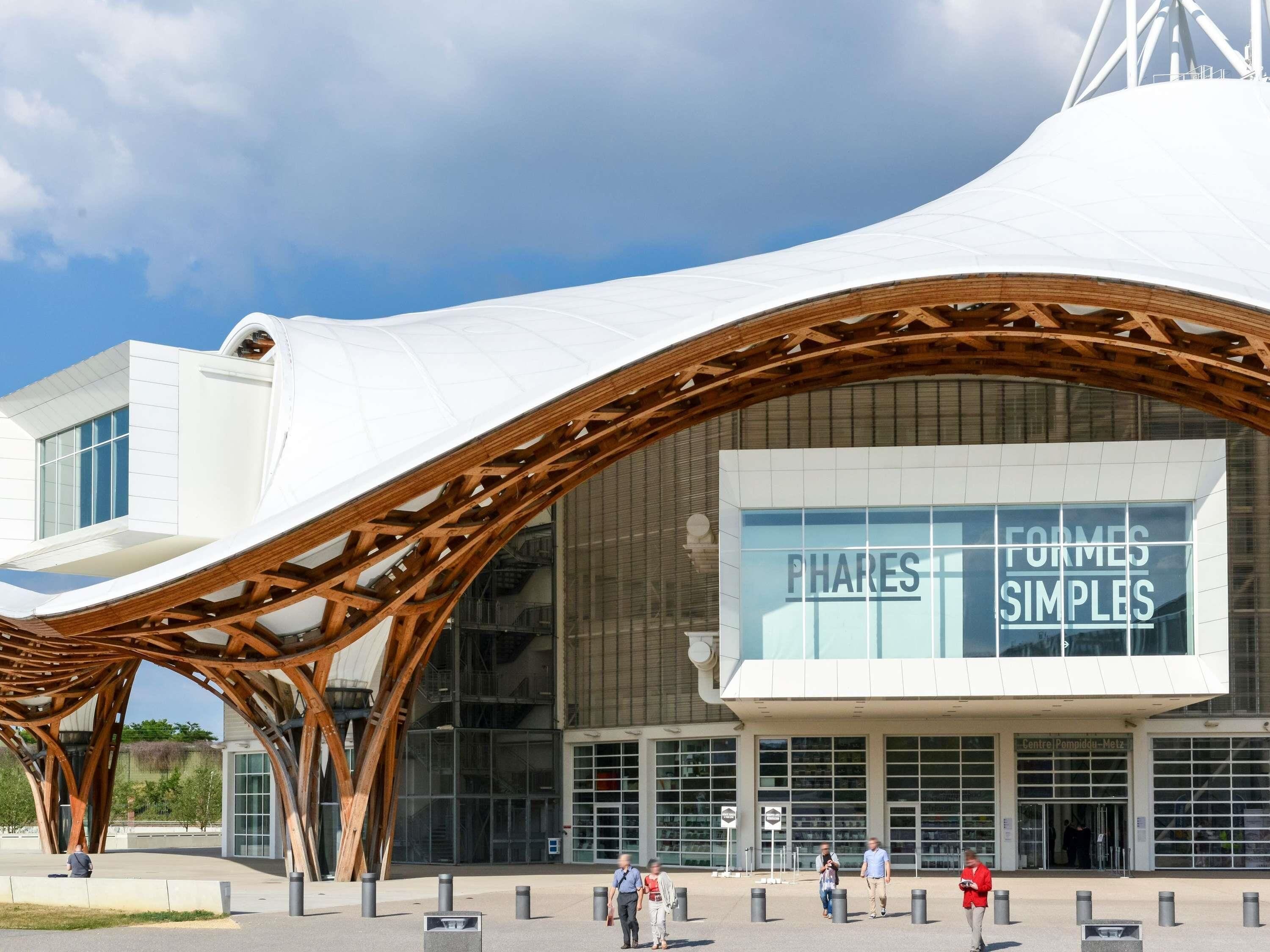 A modern building with a unique curved roof structure and large glass windows.