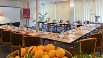 Ein Konferenzraum mit Tischen, Stühlen, Namensschildern, Wasserflaschen und einer Obstschale.