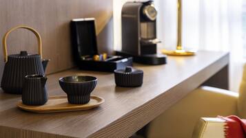 Uma mesa de madeira com jogos de chá de cerâmica preta e uma máquina de café.